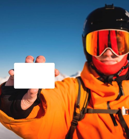 snowboarder-o-esquiador-sosteniendo-un-pase-de-elevacion-en-blanco-en-la-mano-retrato-con-montana-en--scaled-min